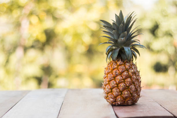 istock Pineapple on wood table with nature background 648849802
