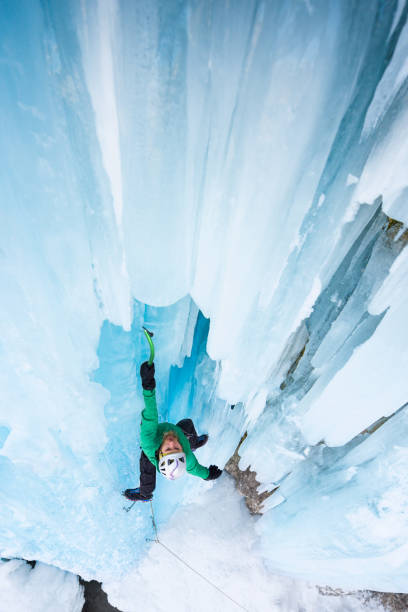 Strong man climbing on blue icicles outdoor High angle view of man ice climbing on frozen waterfall with blue icicles icefall stock pictures, royalty-free photos & images