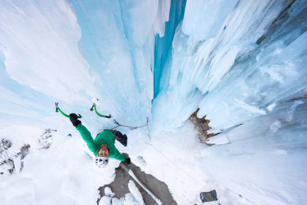カメラに微笑む氷の斧につかまっている喜びに満ちた登山家 - アイスクライミング ストックフォトと画像
