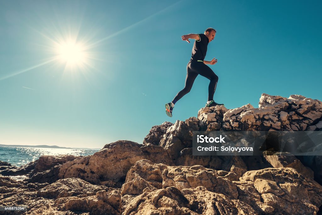 L’homme s’exécute sur le bord de mer rocheux - Photo de Courir libre de droits