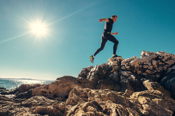 Man runs on rocky sea side Man runs on rocky sea side mountain man stock pictures, royalty-free photos & images