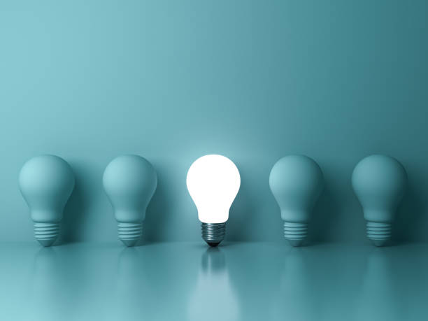 istock One glowing light bulb standing out from the unlit incandescent bulbs on green background with reflection , individuality and different creative idea concepts 648892366
