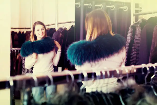 Photo of Pretty woman customer examining new fur neckpiece