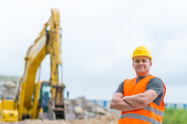 A construction worker in a yellow hard hat is carefully measuring with a tape measure, showcasing his work attire