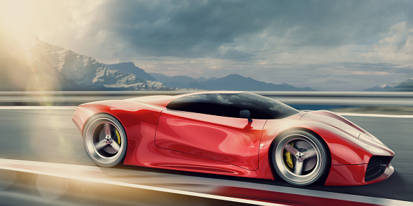 A side view of a generic red sports car travelling at speed with motion blur on wheels. The car is being driven fast on a road on a high altitude outdoor racetrack close to mountains in the background, under a overcast, cloudy evening sky at sunset.