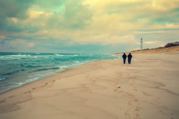 Photo of Silhouette of two man walking on the beach in winter