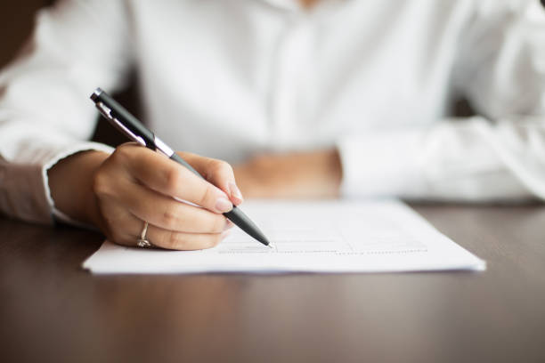 istock Hand of businesswoman writing on document at table 648943108