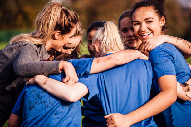 Female Rugby Players Together in a Huddle Young teenage girls smiles as she gathers around with her team mates for a chat during their rugby game sports uniform photos stock pictures, royalty-free photos & images