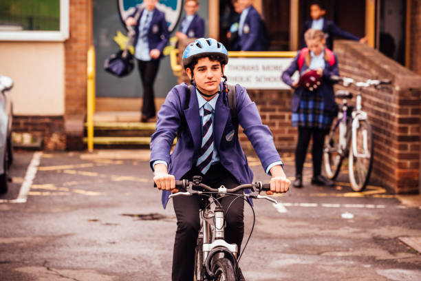 Teenager Cycles to School and Back School children with their bicycles in the school yard. Boy rides his bike away from the school entrance through the schoolyard bicycle cycling school child stock pictures, royalty-free photos & images