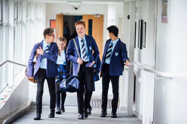 Teenagers Walking to Next Lesson in School Small group of teenage school children walking through school corridor to their next class. school boy in uniform stock pictures, royalty-free photos & images