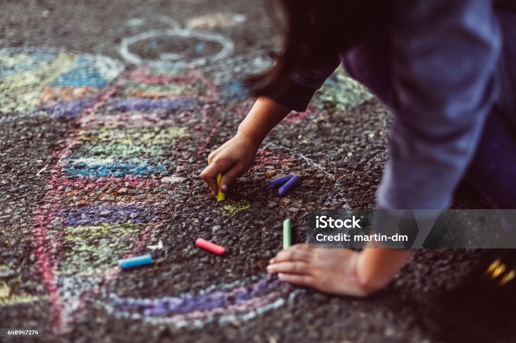 Kid painting on the ground Little girl chalk drawing on asphalt Child Stock Photo