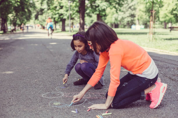 Sisters drawing with chalk in the park