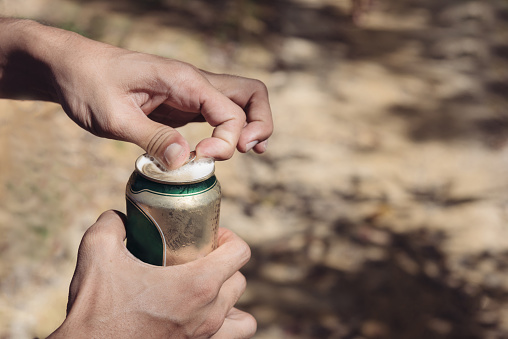 hand man open cans. Hands opening a soda (beer) in selective focus with warm fall color.
