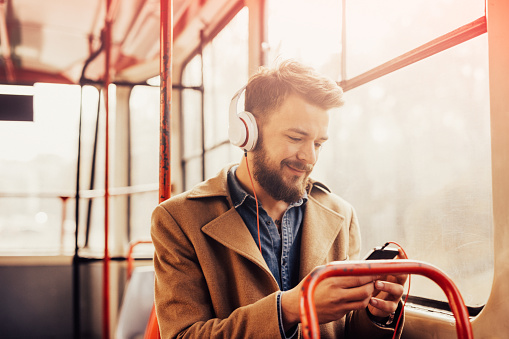 Hombre encantador escuchar música con auriculares en un autobús público photo