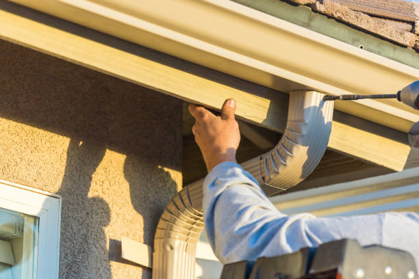 Worker Attaching Aluminum Rain Gutter to Fascia of House. stock photo
