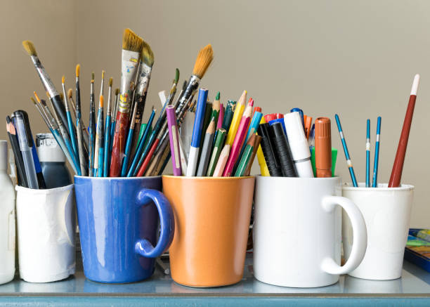 istock Close up of different used paint brushes, sharpened colored pencils, pens, and markers 648964388