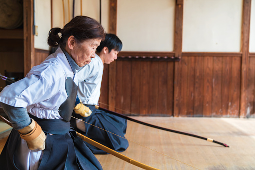 Senior female master archer and her student pausing to show respect before starting their practice together. Okayama, Japan. March 2017