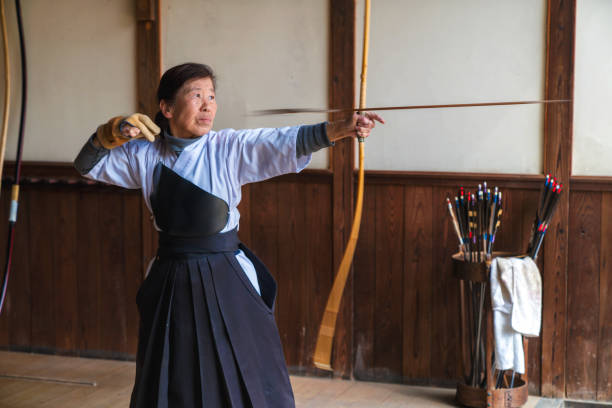 istock Traditional Senior archer looses an arrow from her bow 648967646