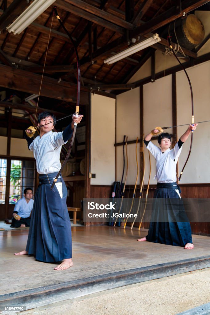 Two young adult archers Two young adult Japanese Kyudo archers preparing to take their shots. Okayama, Japan. March 2017 Kyudo Stock Photo