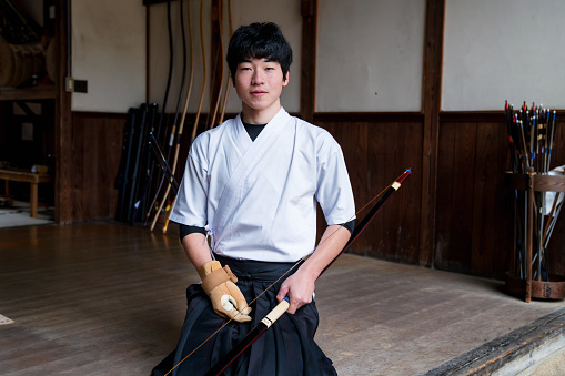 Portrait of a young adult male practicing the traditional Japanese sport of Kyudo, archery. Okayama, Japan. March 2017