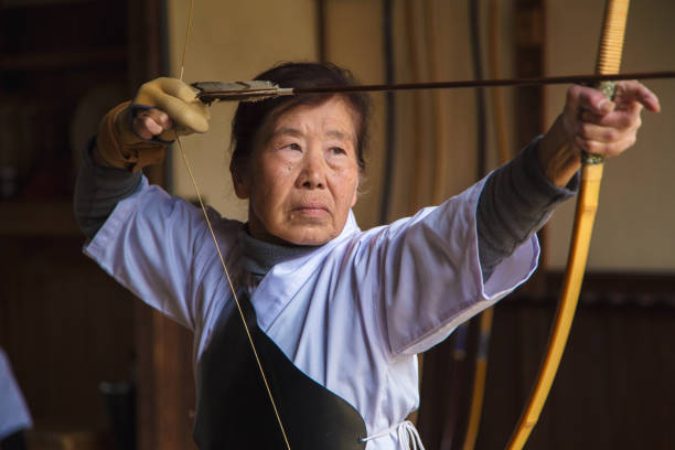シニア女性アーチャー描画彼女の弓 - 弓道 ストックフォトと画像