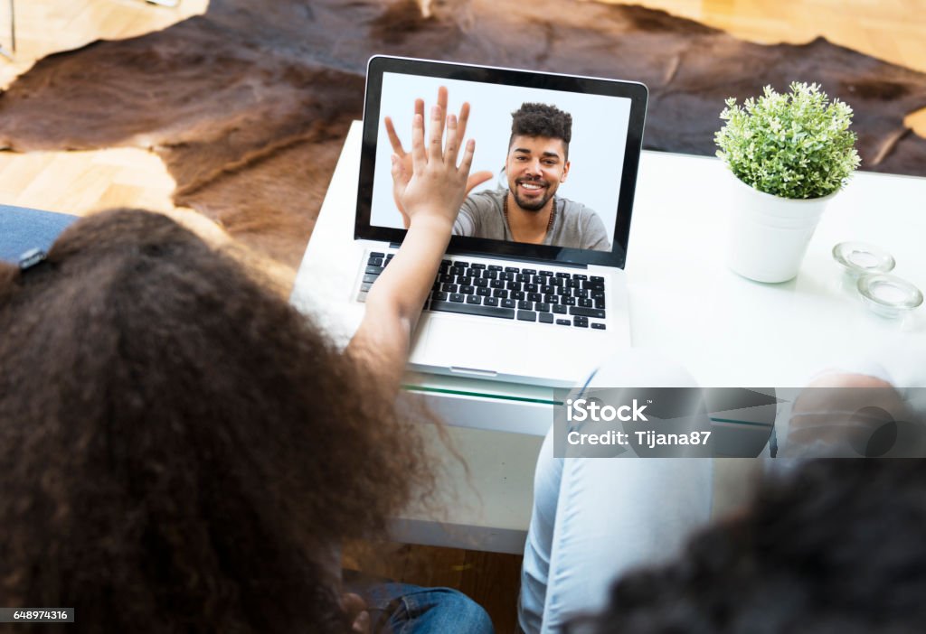 Child video chatting over a laptop with her father Video Call Stock Photo