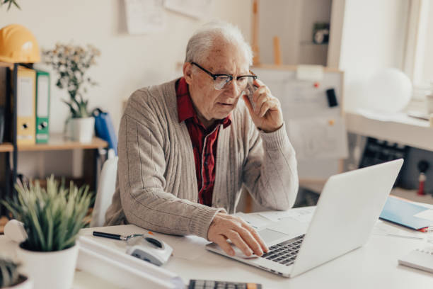 istock Old man using phone and laptop from the office 648977846