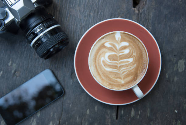 istock cup of hot latte coffee with smart phone and camera 648978528