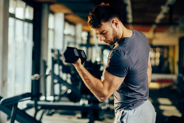 istock Handsome man doing biceps lifting with dumbbell in a gym 648978874