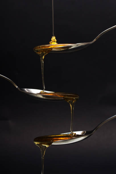 istock Honey pouring from spoon against a dark background 648979070