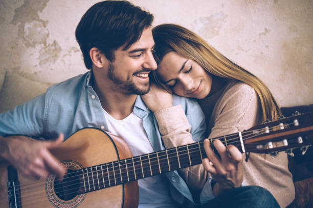 istock young beautiful couple close together with guitar on sofa 648983538