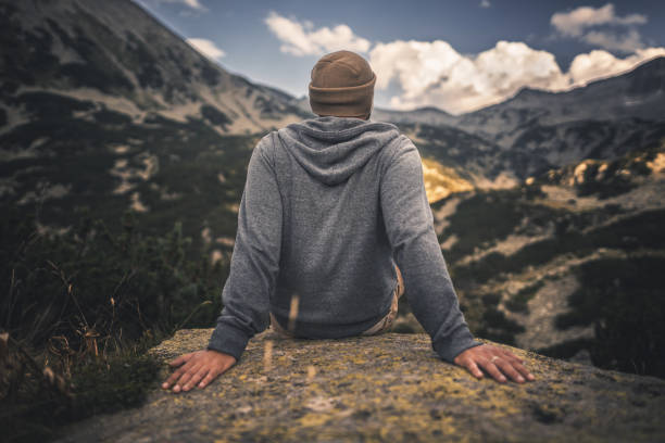 Enjoying majestic mountains and landscape sitting on big rock
