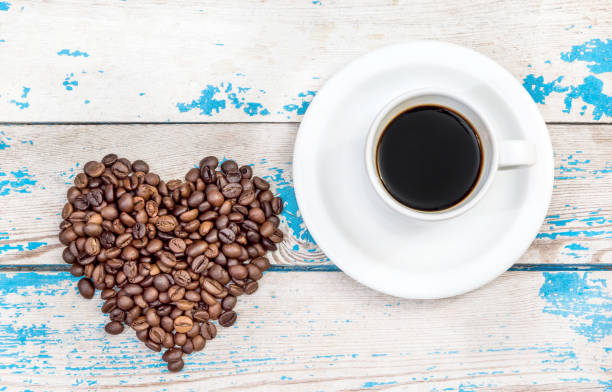 istock Cup with coffee and heart from coffee beans on wooden background. 648986682
