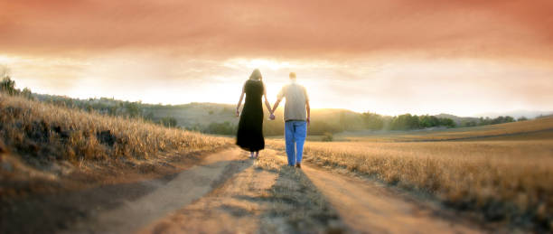 Couple Walking Away at Sunset - Stock image