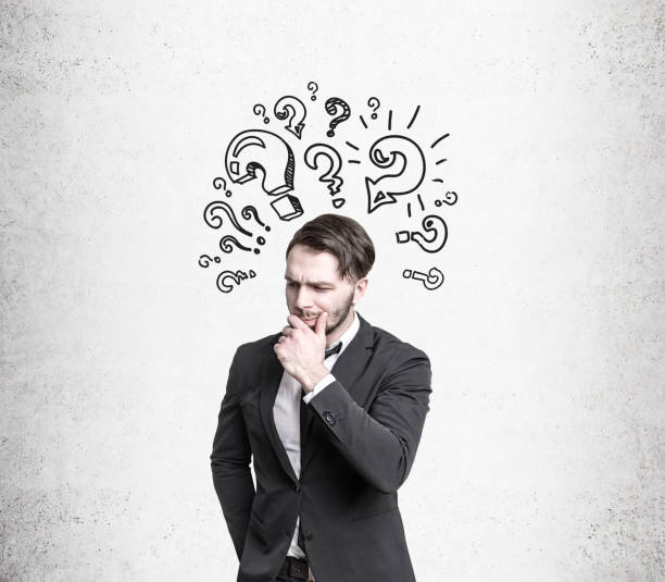 istock Pensive man near question marks on concrete wall 649008938