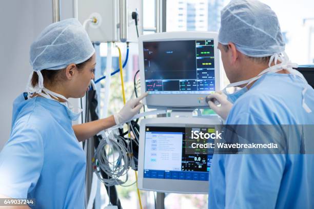 Surgeons Reading Computer Screen Stock Photo - Download Image Now - Medical Equipment, Computer Monitor, Operating Room