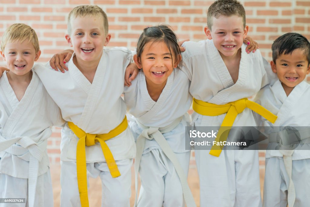 Getting a Yellow Belt A group of elementary age children are taking a martial arts class. They are standing together in a row and are smiling while looking at the camera. Child Stock Photo