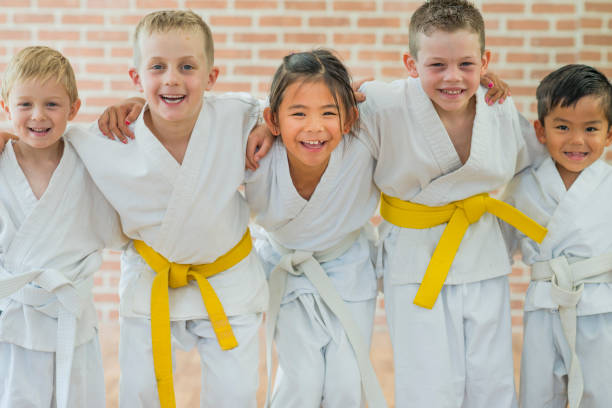 Getting a Yellow Belt A group of elementary age children are taking a martial arts class. They are standing together in a row and are smiling while looking at the camera. karate robe stock pictures, royalty-free photos & images