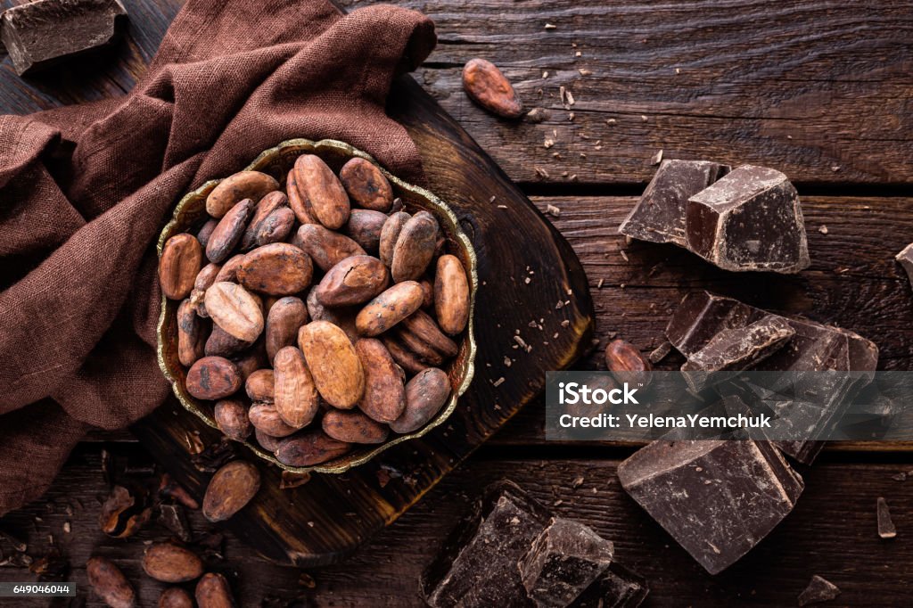 Cocoa beans and chocolate on wooden background Cocoa Bean Stock Photo