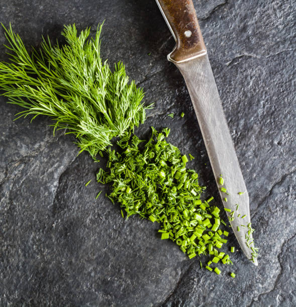 istock Chopped bunch of fresh dill on a black stone background. 649046230