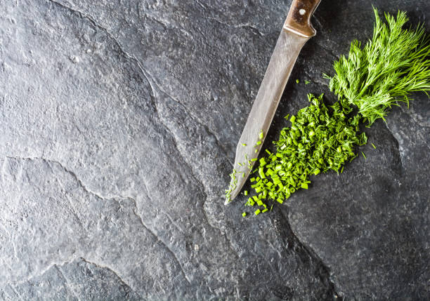 istock Chopped bunch of fresh dill on a black stone background. 649046712
