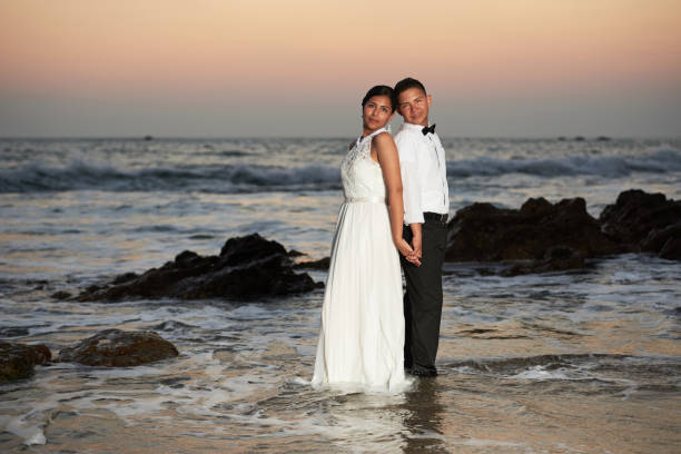 istock Groom and bride stand in sea water 649074776