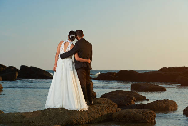 istock Married couple watching sunset on ocean beach 649074908