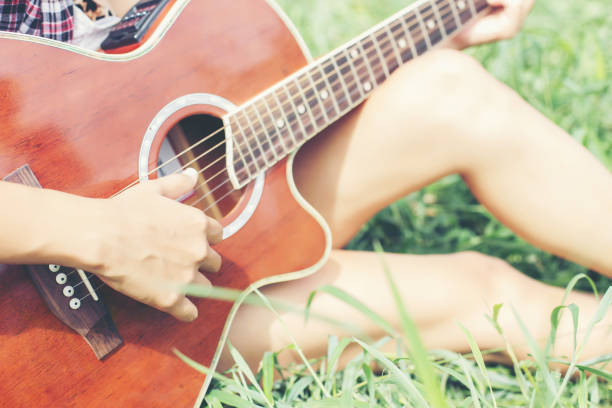 istock Young hipster girl sitting playing a guitar and singing. 649095282