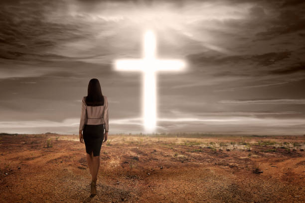 Back view asian woman walking to bright cross shape on dry land background