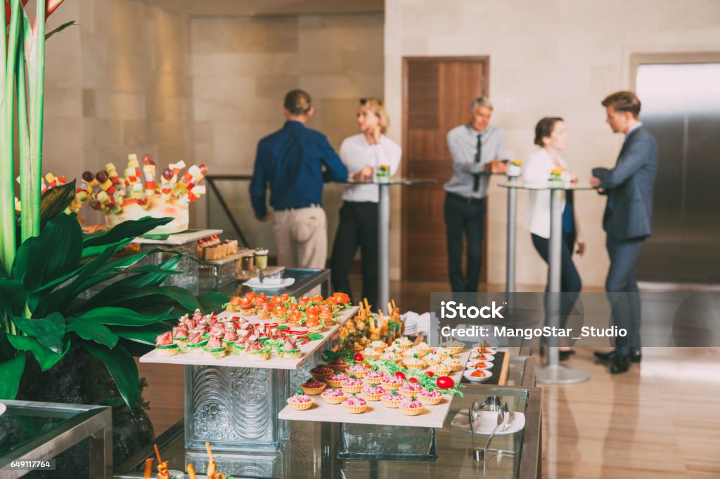 View of Canapes and Tartlets on Buffet Table View of different canapes, tartlets and snacks on buffet table in restaurant. Business people eating and talking in background. Catering concept Breakfast Stock Photo