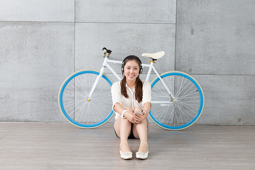 young pretty chinese woman with bike near wall