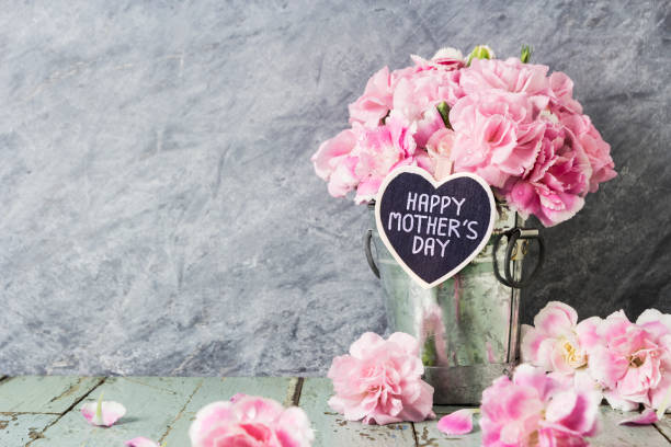розовые цветы гвоздики в цинковом ведре со счастливыми матерями день письмо на деревянном сердце - венчик лепесток фотографии стоковые фото и изображения