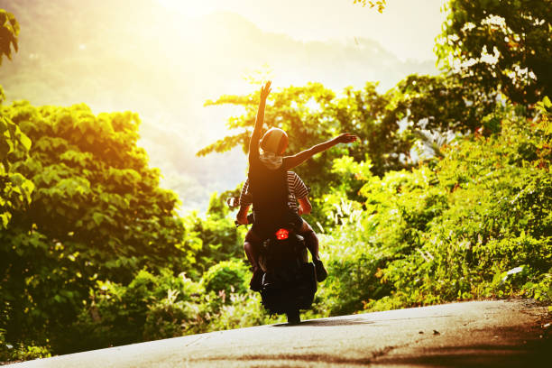 Happy couple tripping by motorcycle on tropical road at sunset time