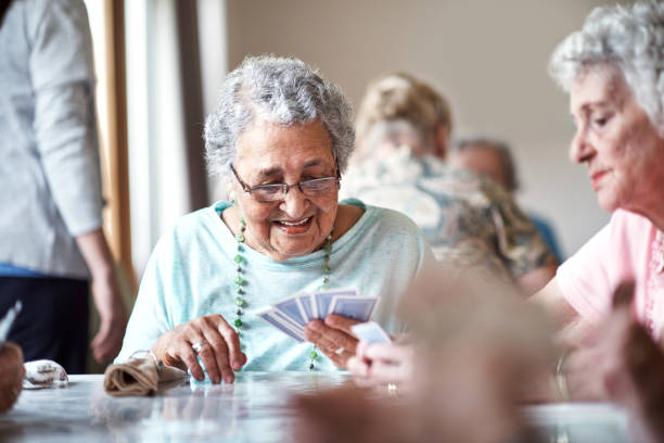 I can't lose with this hand Shot of a group of seniors playing a board game in their retirement home leisure equipment stock pictures, royalty-free photos & images